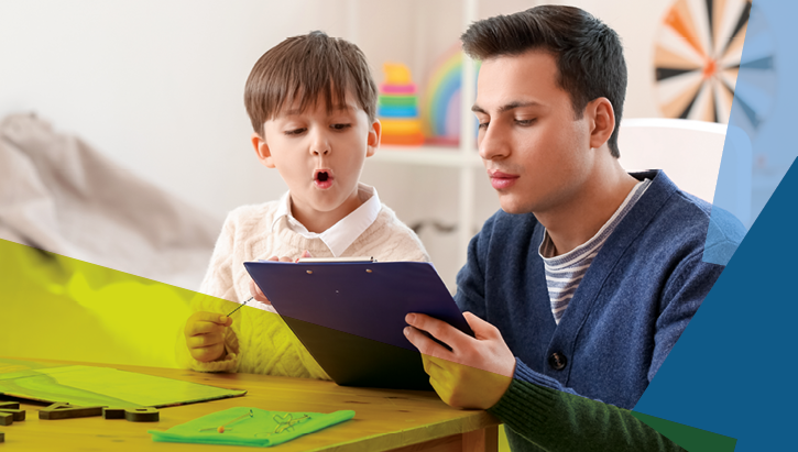 Junger Mann lernt mit einem Jungen in einem Zimmer mit Spielsachen